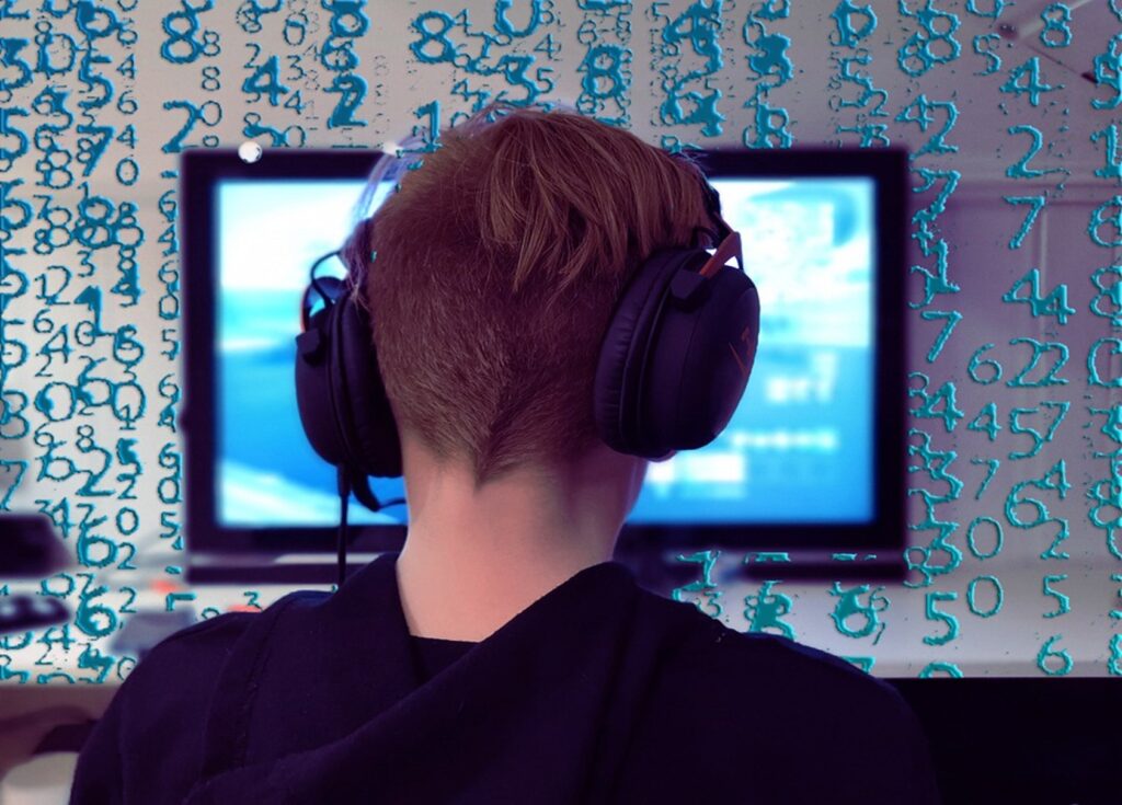 person in front of computer monitor wearing headphones