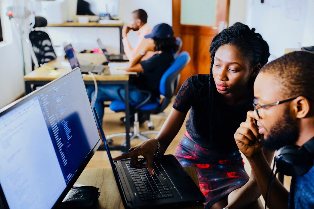 a man and woman working together at computer