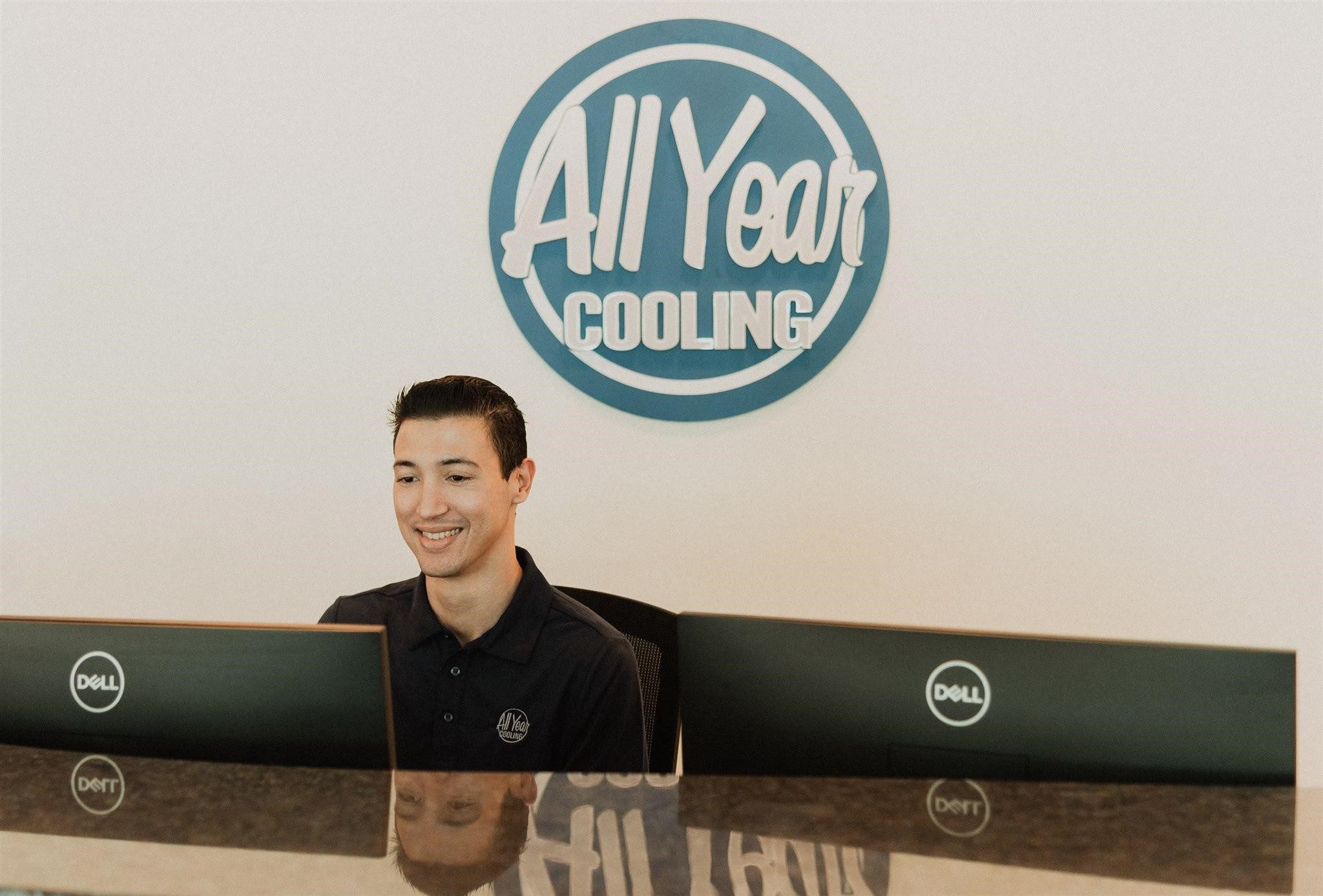 An All Year Cooling employee sitting at a desk helping a customer get approved for internal financing.