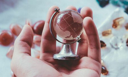 A man holds a glass globe in his hand, representing Elijah Norton’s global expansion efforts