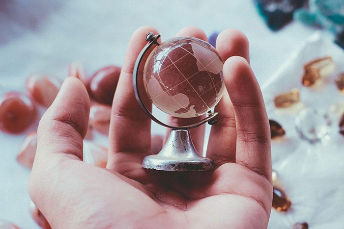 A man holds a glass globe in his hand, representing Elijah Norton’s global expansion efforts