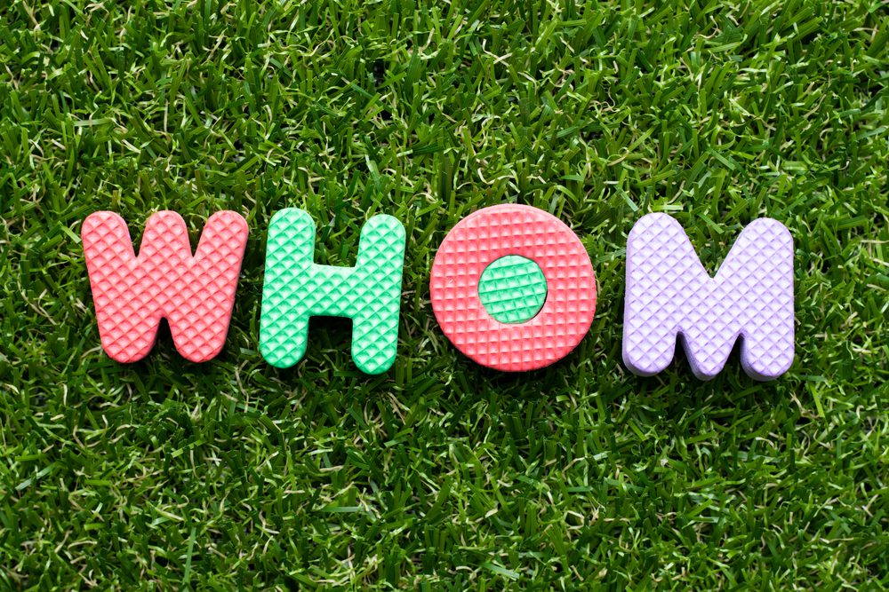 Toy foam letter in word whom on green grass background