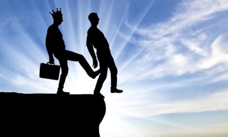 Silhouette, A male egoist with a crown is pushing another man into the abyss with his foot. Concept of selfishness and betrayal in business