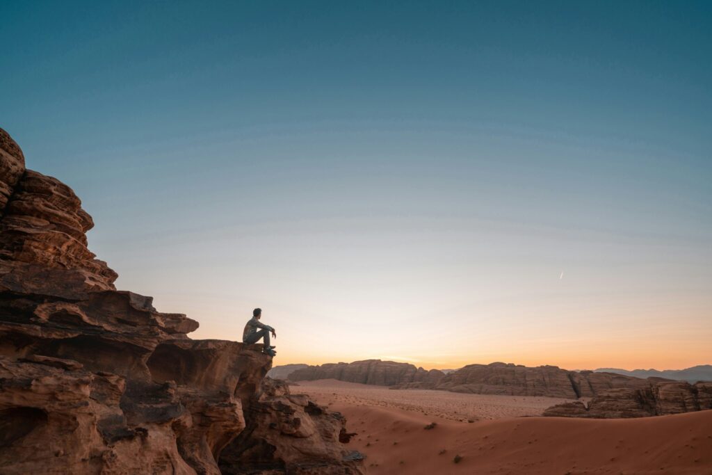A person travelling and sitting with a sunset
