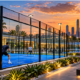 Outdoor blue padel court with glass walls and metal framing at sunset