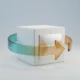 Minimal 3D cube encircled by a translucent arrow ring, symbolizing customer feedback refining a product on a soft neutral background.