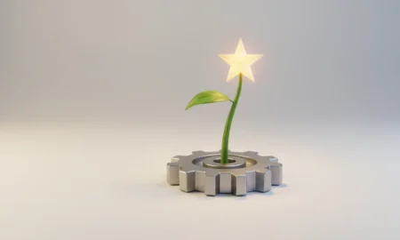 Steel gear sprouting a single green shoot topped with a golden star on a soft neutral background.