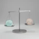 Minimalist balance scale with two identical glowing spheres, symbolizing a tough choice, on a soft neutral background.