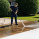 Worker pressure washing driveway while wearing safety glasses