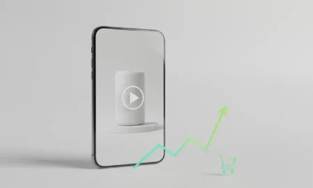 Smartphone showing a product video with a rising sales graph and shopping cart icon on a soft neutral background.