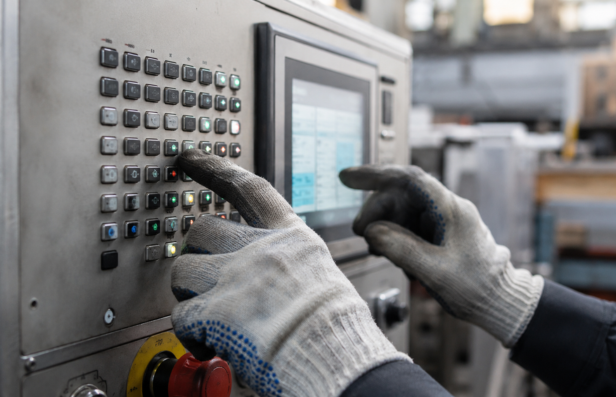 Gloved hand struggling with small industrial control buttons