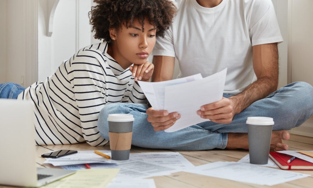 Couple reviewing household bills and finances while exploring rent payment reporting services to build credit in 2026.