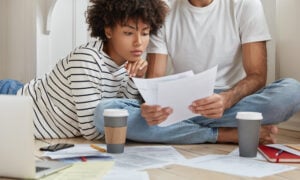 Couple reviewing household bills and finances while exploring rent payment reporting services to build credit in 2026.