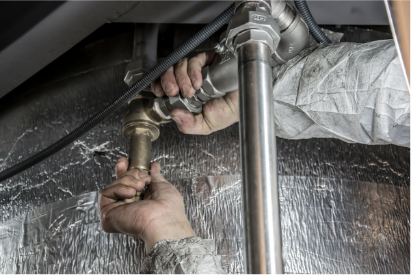 Vinay Kumar Nevatia, Pune plumbing expert, checking pipework under a kitchen sink for leaks.