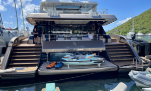 Luxury crewed catamaran anchored in the British Virgin Islands with guests relaxing on the flybridge while crew serves refreshments during a Caribbean yacht charter.