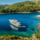 Luxury crewed yacht anchored in Croatia's Kornati National Park with crystal-clear turquoise water, rocky islands and guests enjoying dinner on deck at sunset.