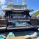 Luxury crewed catamaran anchored in the British Virgin Islands with guests relaxing on the flybridge while crew serves refreshments during a Caribbean yacht charter.