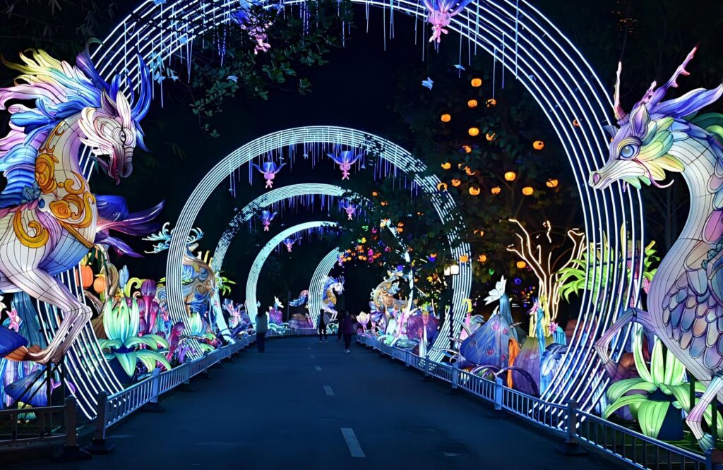 Technicians pre-installing and testing a large illuminated peacock lantern display inside a production facility