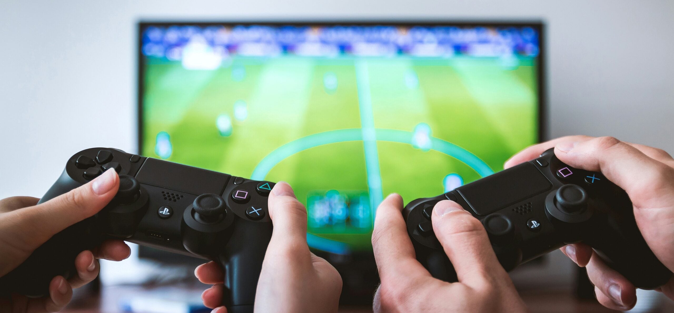 Two players holding game controllers playing a football game on TV multiplayer gaming