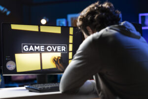Gamer facing a “Game Over” screen, illustrating gaming account hacking, data breaches, and the importance of online gaming account security.