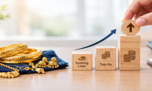 Gold jewelry beside wooden blocks showing existing loan top-up with upward arrow