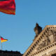 German Reichstag building in Berlin with German flag waving under a clear blue sky